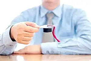 Masa başında mezuniyet kepi tutan kişi – 2025 yılı Mart ve Ekim doçentlik başvuru tarihleri ve belgeler.