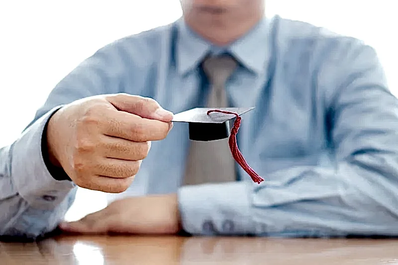 Masa başında mezuniyet kepi tutan kişi – 2025 yılı Mart ve Ekim doçentlik başvuru tarihleri ve belgeler.