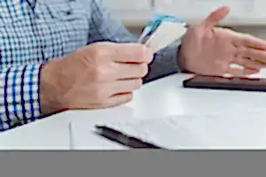 Belgeler ve Türk lirası banknotları tutan kişi – 2025 doçentlik başvurusu ücreti, evrak süreci ve ödeme yöntemleri.