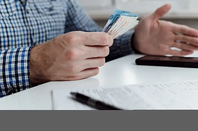 Belgeler ve Türk lirası banknotları tutan kişi – 2025 doçentlik başvurusu ücreti, evrak süreci ve ödeme yöntemleri.