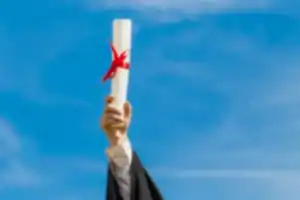 Mavi gökyüzüne doğru uzatılmış, kırmızı kurdeleyle bağlanmış bir diploma rulosu, mezuniyet ve akademik başarıyı simgeleyen görsel.