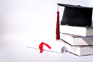 Kitap yığını üzerindeki mezuniyet kepi ve kırmızı kurdeleli diploma – yurt dışı denklik başvurusu ve STS sınavı iptal davası.