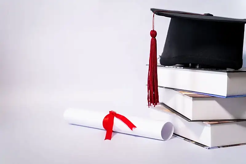 Kitap yığını üzerindeki mezuniyet kepi ve kırmızı kurdeleli diploma – yurt dışı denklik başvurusu ve STS sınavı iptal davası.