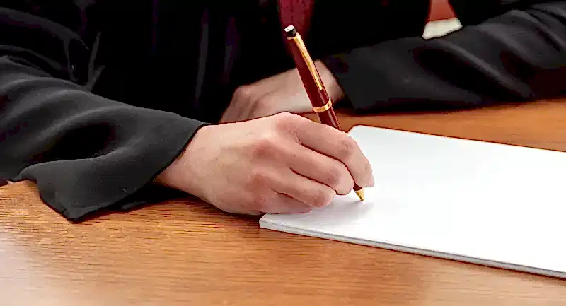 Cübbe giymiş akademisyenin doçentlik başvurusu için dilekçe yazması – jüri değerlendirmesi, puanlama ve yeniden başvuru süreciyle ilgili görsel.