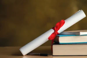 Kırmızı kurdeleyle bağlanmış bir diploma rulosu, yanında bir yığın hukuk kitabı ve bir kalemle akademik başarıyı ve hukuki eğitimi temsil eden görsel.