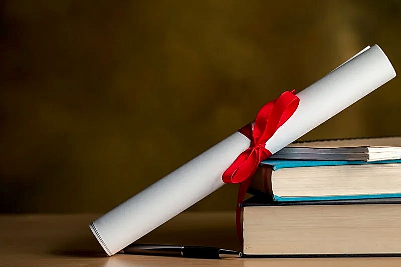 Kırmızı kurdeleyle bağlanmış bir diploma rulosu, yanında bir yığın hukuk kitabı ve bir kalemle akademik başarıyı ve hukuki eğitimi temsil eden görsel.