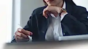 Profesyonel bir takım elbise giymiş bir hukukçunun veya danışmanın elinde stylus kalemle belge veya tableti incelediği, derinlemesine düşünce anını gösteren yakın çekim.