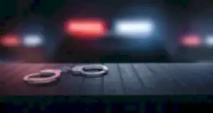 Loş ortamda masada duran kelepçe ve polis ışıkları – suç duyurusu süreci, şikayet dilekçesi ve hukuki başvuru yolları.