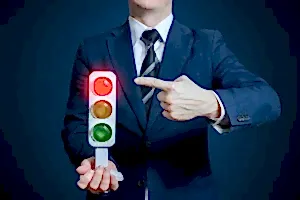 Kırmızı ışığı gösteren takım elbiseli kişi – hukuka aykırı trafik cezalarına itiraz süreci ve avukat desteği.