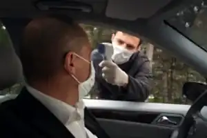 Trafik polisi, durdurduğu arabanın sürücüsünün ateşini ateş ölçer ile ölçüyor.