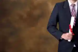 Takım elbiseli kişi elinde kırmızı kurdeleli diploma tutuyor – YÖK denklik başvurusu, belge süreci ve yurt dışı diploma geçerliliği.